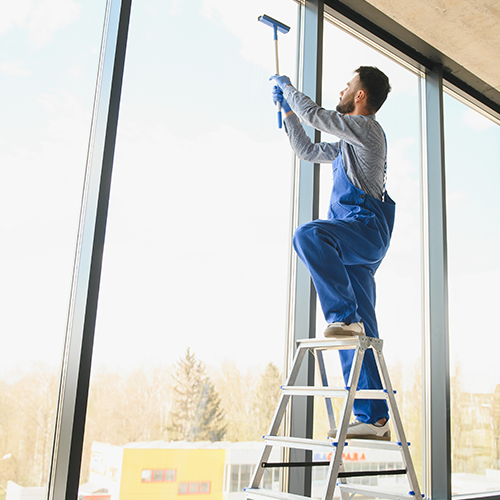 Personne nettoyant des vitres d'un bureau ou d'une habitation en tenue de travail, nettoyage pour les professionnels
